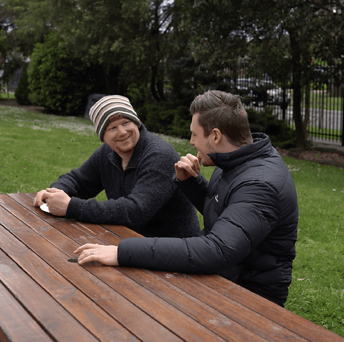Two people having a conversation at a table outdoors